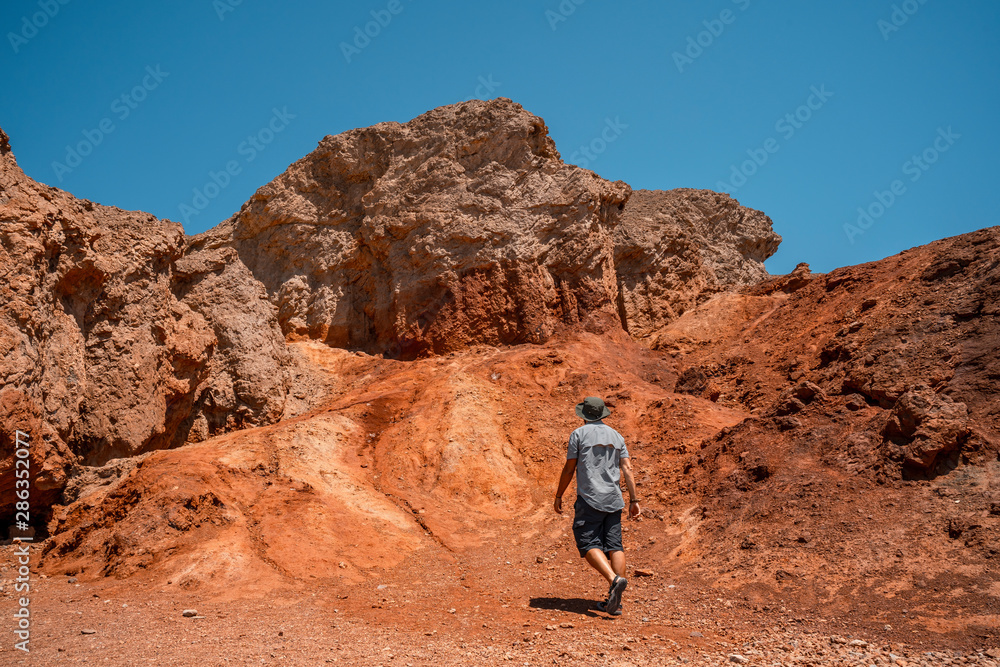 A man starting the Golden Canyon trail and the red stones in the background, California. United States