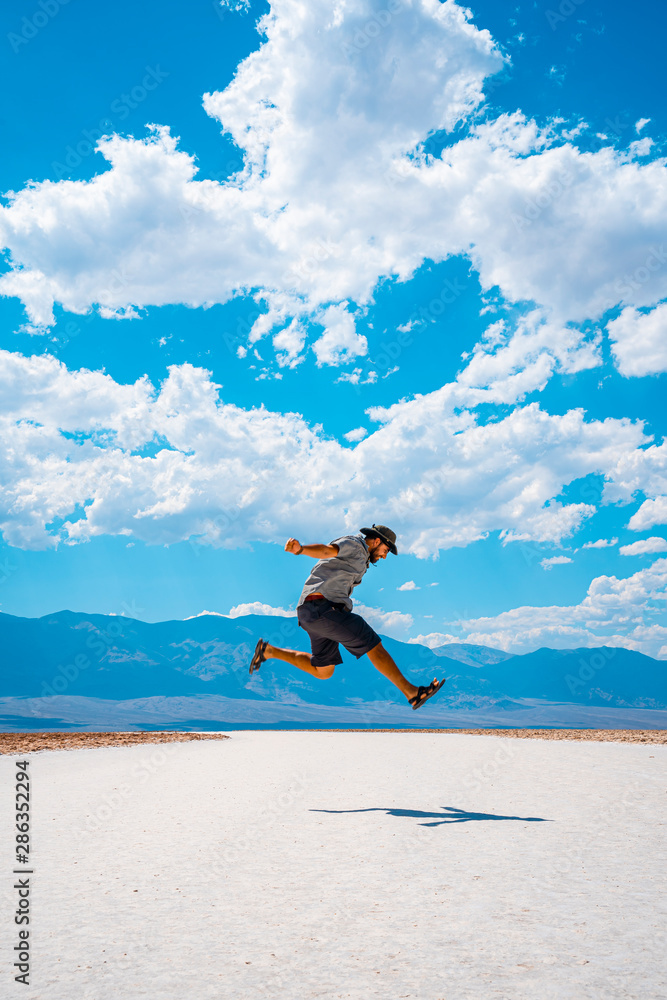 Death Valley, California / United States »; August 2019: A young man jumping with a blue shirt on the white salt of Badwater Basin Death Valley, California / United States »; August 2019: A young man jumping with a blue shirt on the white salt of Badwater Basin