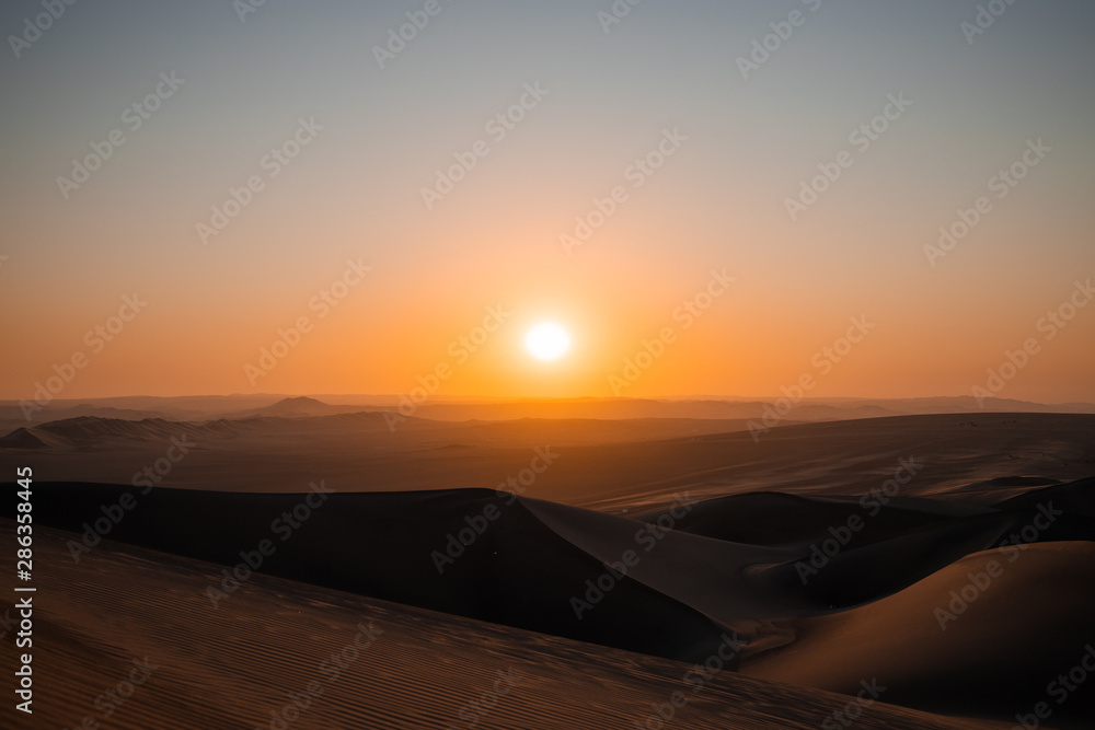 The sun is setting at the desert of Ica, Peru
