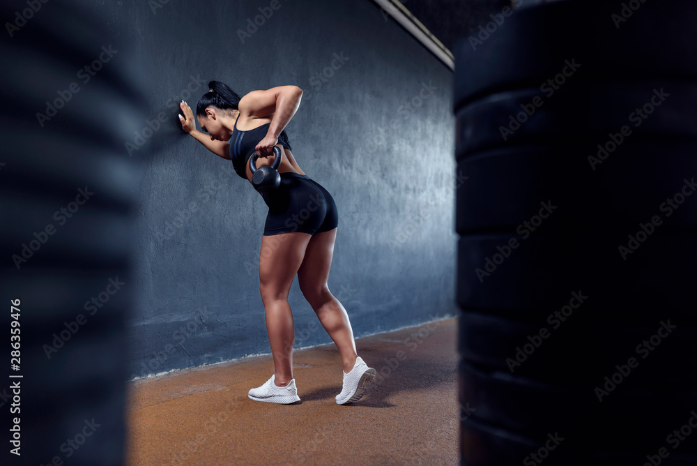 Sport active woman make her workout on a gym with weights - kettlebell. Sexy muscular girl, with black hair.