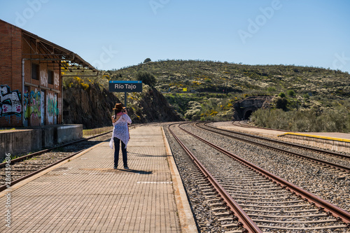 A young woman wearing a cowboy hat takes a photograph of the Extremadura railway track near Garrovillas de Alconetar