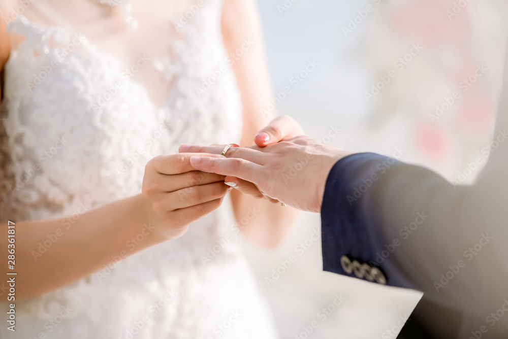 Wedding rings.She Put the Wedding Ring on Him.Close up bride Put the Ring on Groom. Wedding ceremony and wedding decoration. Wedding rings.She Put the Wedding Ring on Him.Close up bride Put the Ring on Groom. Wedding ceremony and wedding decoration.