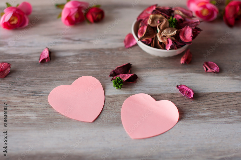 Dry air petals pink roses lie on the table in a white Cup, near with them lie pink paper hearts Dry air petals pink roses lie on the table in a white Cup, near with them lie pink paper hearts
