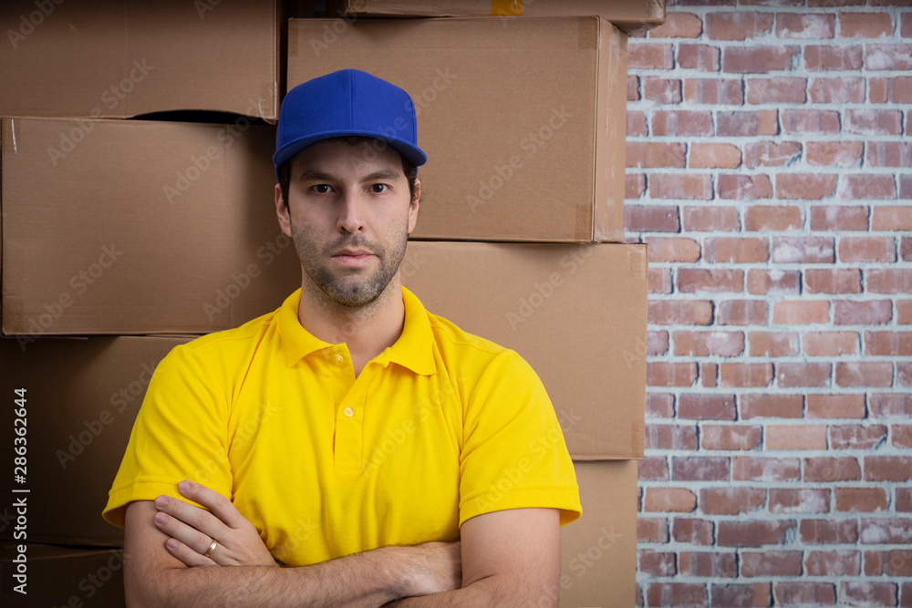 Brazilian mailman with arms crossed in a deposit with a a lot of boxes. Brazilian mailman with arms crossed in a deposit with a a lot of boxes.