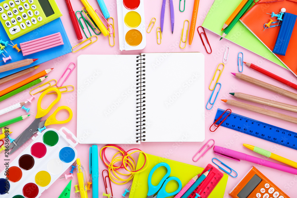 Different school supplies with opened notebook on pink background Different school supplies with opened notebook on pink background