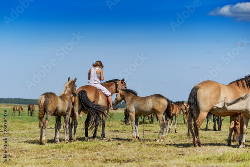 A girl rides a horse across a farm field.
