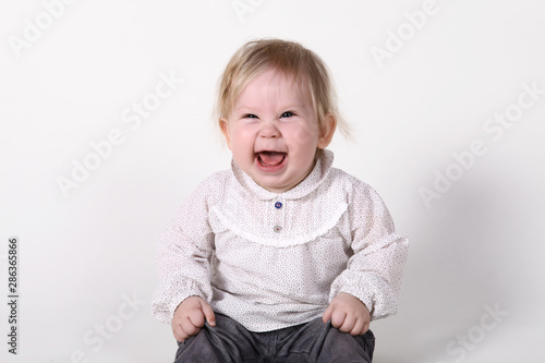 European baby or toddler sits and smiles in front of a white background