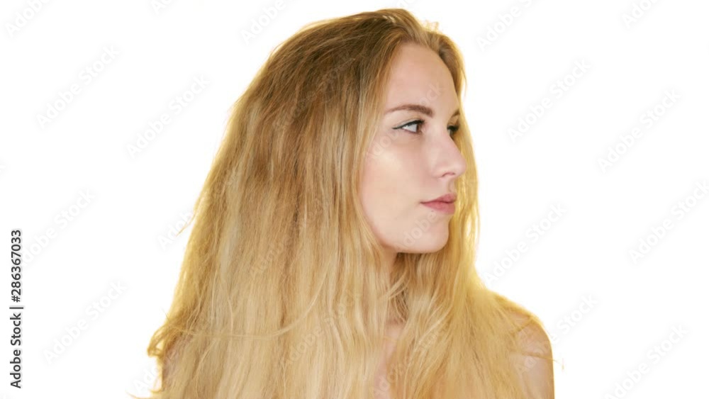Pretty blonde girl looks from side to side, posing against a white backdrop, touching her face with her hands Pretty blonde girl looks from side to side, posing against a white backdrop, touching her face with her hands