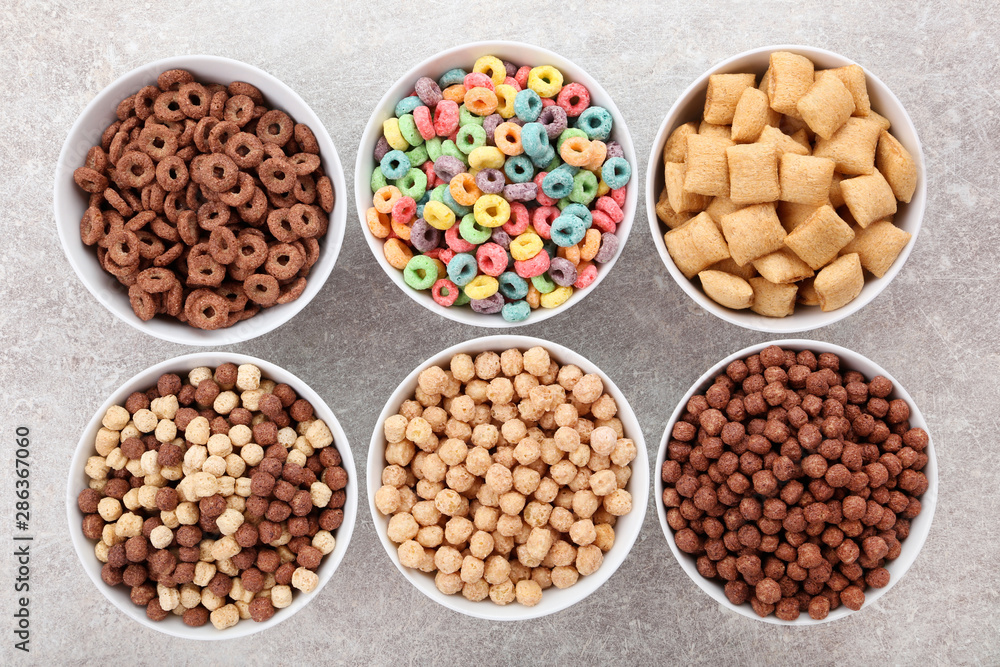 Various corn flakes in bowls on grey background Various corn flakes in bowls on grey background