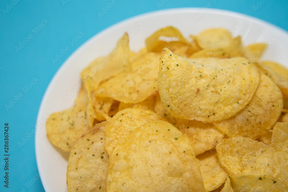 chips in white plate on blue background chips in white plate on blue background