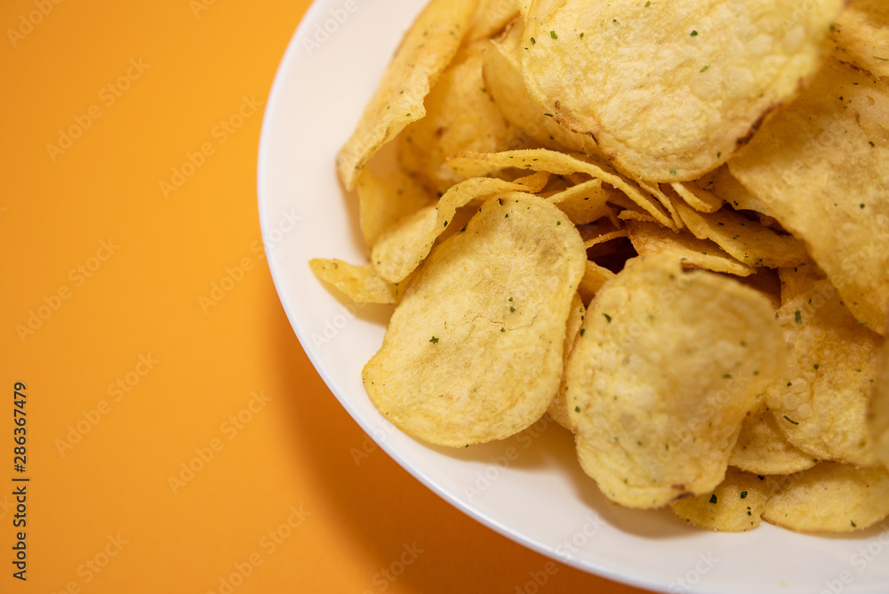 chips in white plate on yellow background chips in white plate on yellow background