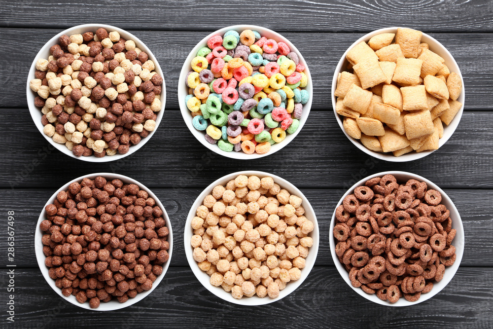 Various corn flakes in bowls on black wooden table Various corn flakes in bowls on black wooden table