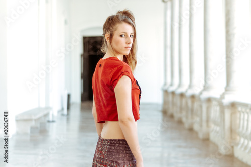 Blond girl photographed in an old building with white walls and natural poses.