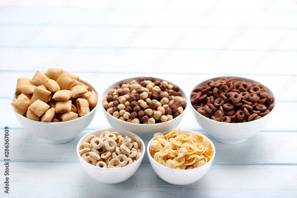 Various corn flakes in bowls on white wooden table Various corn flakes in bowls on white wooden table