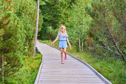 Child blond girl enjoying nature in Jezerni slat (Lake Moor) in National Park Sumava (Bohemian Forest), Czech Republic