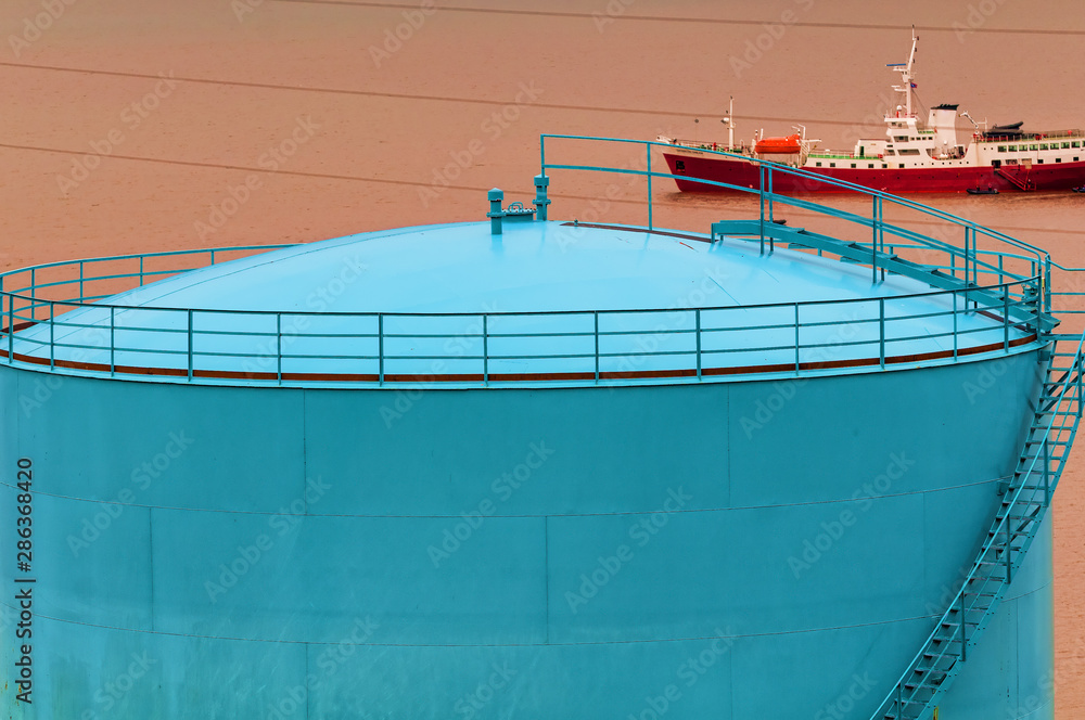 Colorful fuel storage tanks with a shipin the background on the coastline of Longyearbyen, Svalbard, Norway