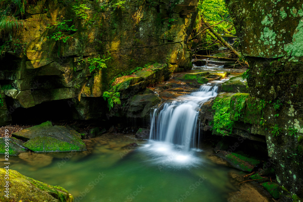 Waterfalls in green forest during a summer, exposure with a long time. The river Satina in the Beskydy Mountains, Czech Republic, Europe. Waterfalls in green forest during a summer, exposure with a long time. The river Satina in the Beskydy Mountains, Czech Republic, Europe.