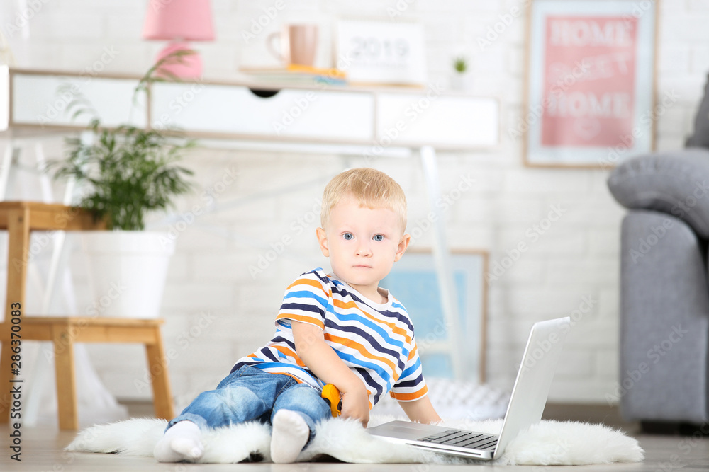 Little boy with laptop computer sitting on white carpet at home Little boy with laptop computer sitting on white carpet at home