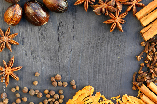 Border of spices on wooden background.
