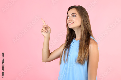 Young woman in blue dress on pink background