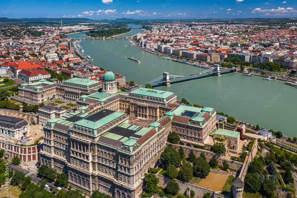 Fototapeta premium Budapest, Hungary - Aerial skyline view of Buda Castle Royal Palace on a bright summer day with Szechenyi Chain Bridge, River Danube and Parliament of Hungary at background taken with a drone
