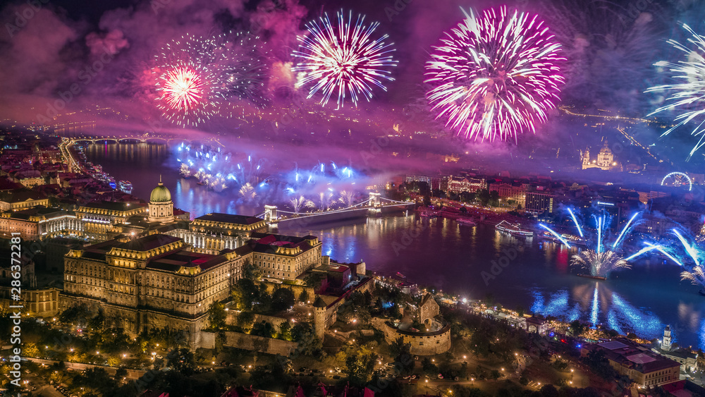 Fototapeta premium Budapest, Hungary - Aerial panoramic view of Budapest with illuminated Buda Castle Royal Palace, St.Stephen's Basilica and Szechenyi Chain Bridge by night with fireworks