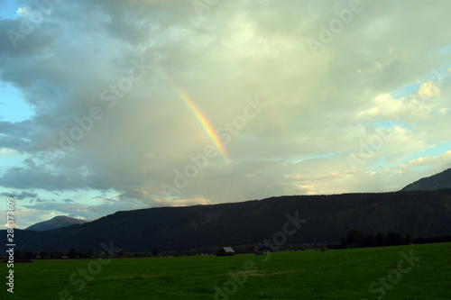 rainbow over field with blue sky and clouds