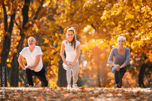 Fototapeta Naklejka Na Ścianę i Meble -  Senior man and woman and young female instructor  workout on fresh air. Outdoor activities, healthy lifestyle, strong bodies, fit figures. Stylish, modern sportswear. Different generations