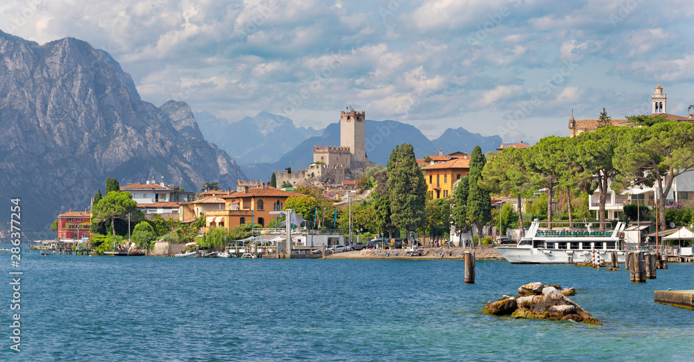 Malcesine - The promenade over the Lago di Garda lake with the town and castle in the background. - obrazy, fototapety, plakaty 