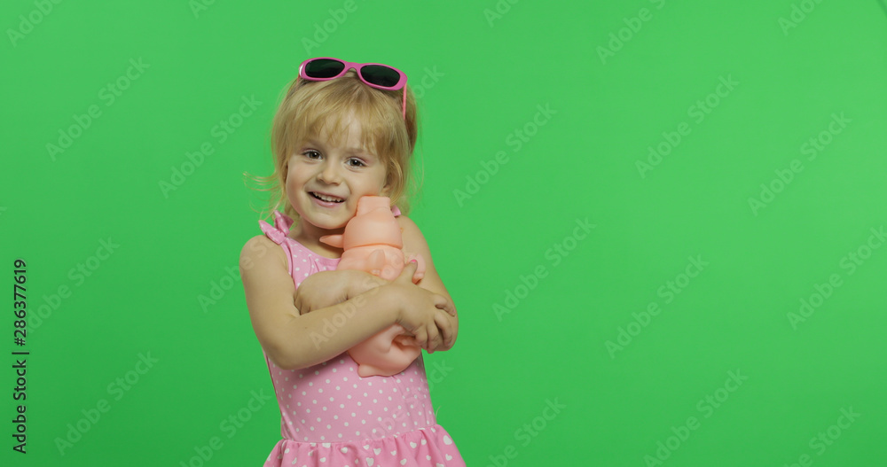 Child in pink swimsuit playing with a toy pig. Chroma Key Child in pink swimsuit playing with a toy pig. Chroma Key