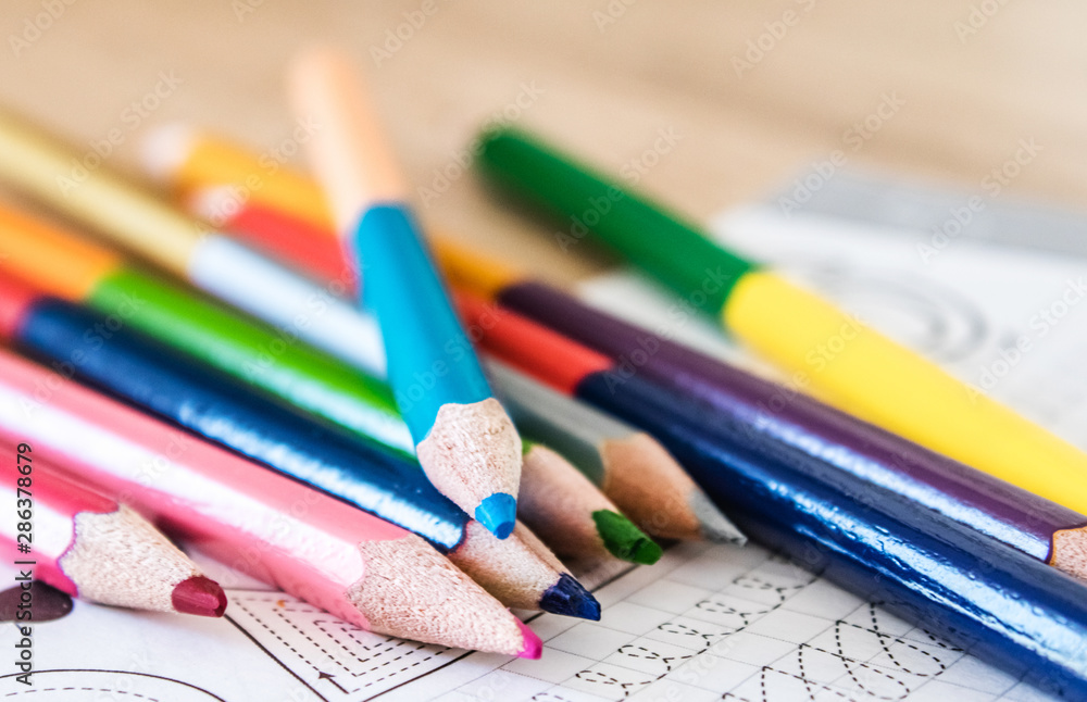 Naklejka premium Colored pencils scattered on a school notebook.