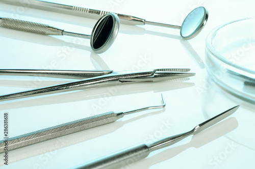 Dentist equipment  kornzange or forceps  two dental mirrors  cement spatula  explorer. Dental tools on white surface  closeup.