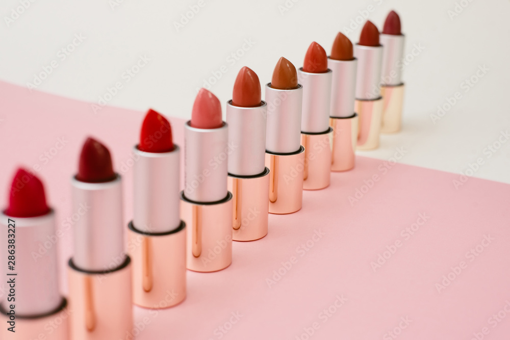 a lot of different lipsticks stand on a beige and pink background. Pattern and concept of beauty, cosmetics, women's accessories. Shades of lipstick tubes a lot of different lipsticks stand on a beige and pink background. Pattern and concept of beauty, cosmetics, women's accessories. Shades of lipstick tubes