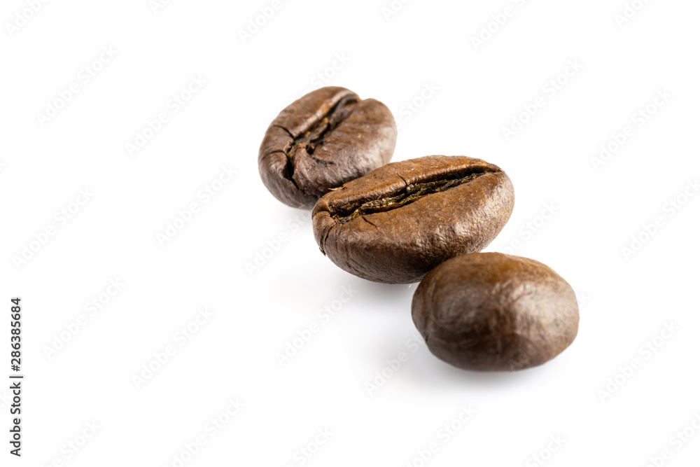 Three shiny fresh roasted coffee beans isolated on white background. Coffee background or texture concept. Three shiny fresh roasted coffee beans isolated on white background. Coffee background or texture concept.