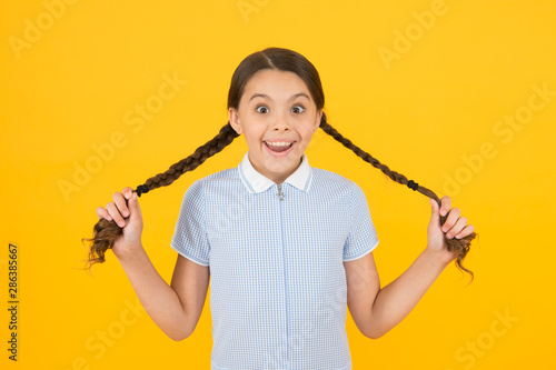 Cute braids. Tender schoolgirl on yellow background. Tidy hairstyle. Little girl with cute braids. Beautiful braids. Braided hairstyle concept. Girl with braided hair style. Hairdresser salon