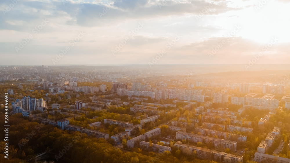 Shot of a beautiful city located at the edge of a forest, and a blue sky, during sunrise.