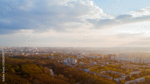 Shot of a city located at the edge of a forest, and a cloudy white sky, during a majestic sunrise.