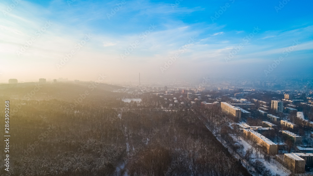 Aerial view of a city and a small forest, during a cold, snowy winter.