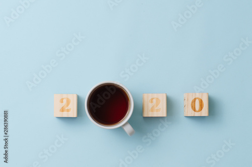 Fototapeta Naklejka Na Ścianę i Meble -  Happy new year composition. 2020 number and tea in a cup over blue background.
