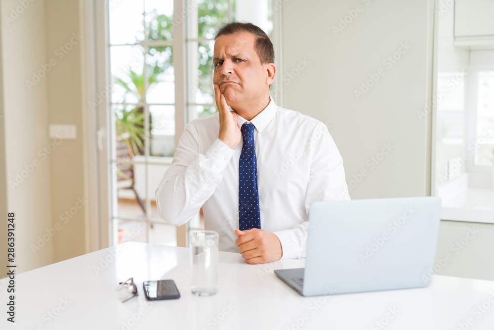 Middle age business man working with computer laptop thinking looking tired and bored with depression problems with crossed arms.