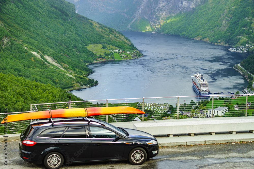 Car with canoe on top roof against fjord
