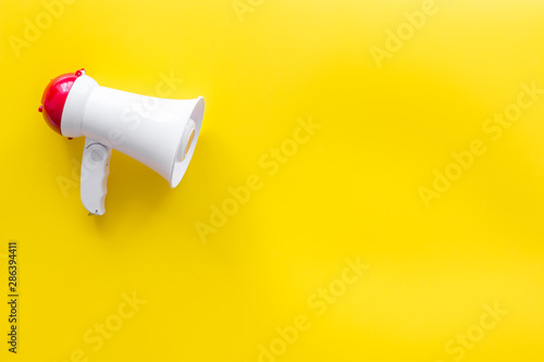 megaphone for advertising and announcement on yellow background top view copyspace