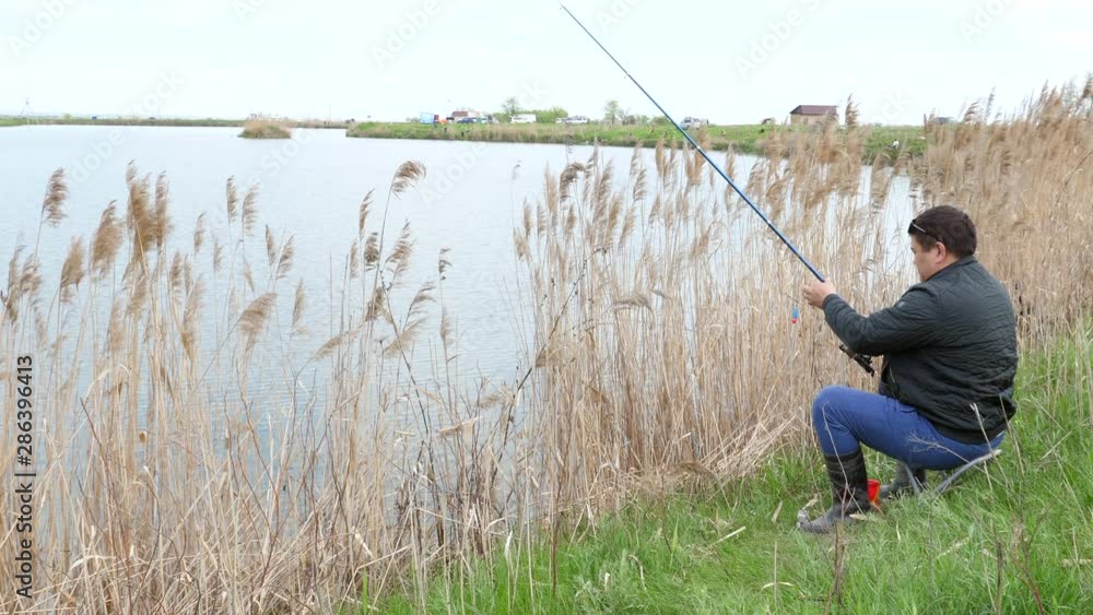 young asian Fisherman sitting on a shore lake casts a Fishing Rod into the lake. young asian Fisherman sitting on a shore lake casts a Fishing Rod into the lake.