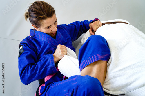 Omoplata submission judo bjj brazilian jiu jitsu training sparring two women female fighters in training wearing kimono gi photo