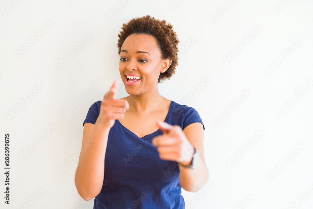 Young beautiful african american woman over white background pointing fingers to camera with happy and funny face. Good energy and vibes. Young beautiful african american woman over white background pointing fingers to camera with happy and funny face. Good energy and vibes.