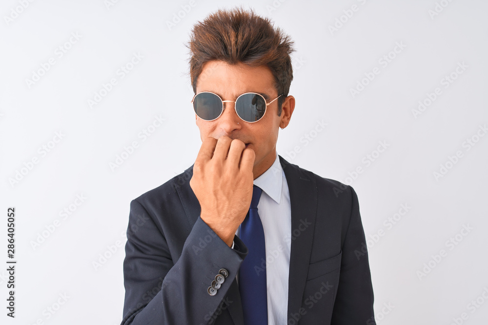 Young handsome businessman wearing suit and sunglasses over isolated white background looking stressed and nervous with hands on mouth biting nails. Anxiety problem.