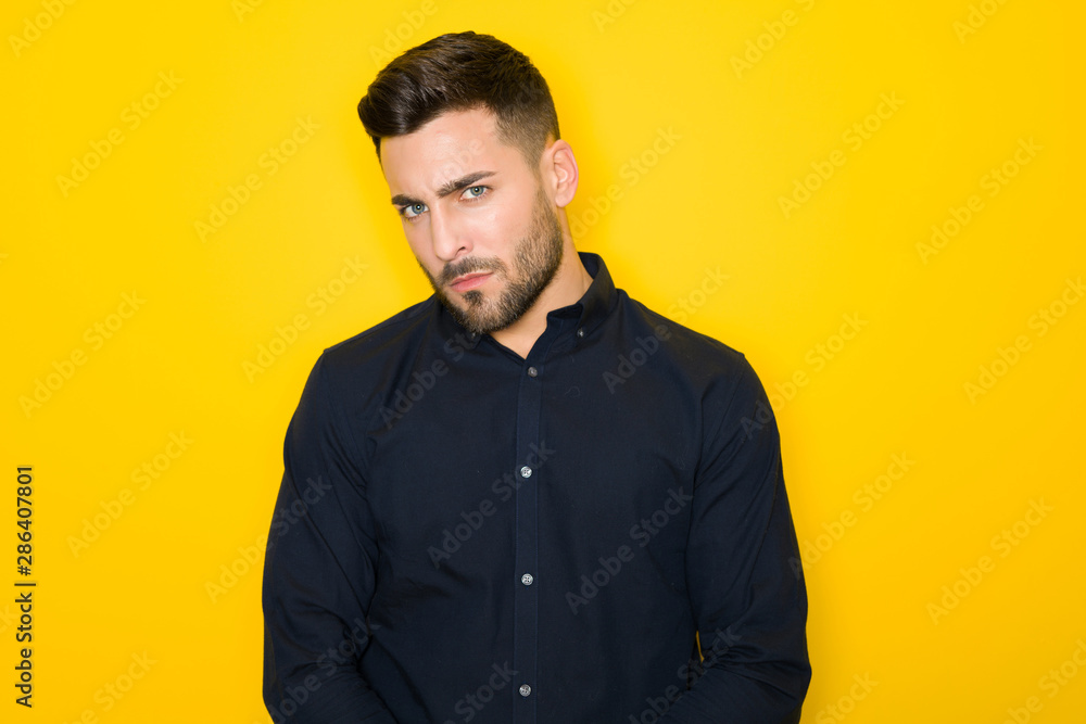 Fototapeta premium Young handsome man possing and modeling over yellow isolated background