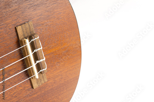 Close-up of dark wooden ukulele music instrument Hawaiian guitar body isolated over white background with copy space. 