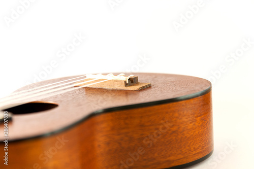 Close-up bridge of dark brown wooden ukulele Hawaiian guitar isolated on white background.