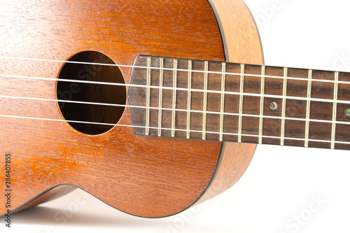 Close-up dark brown wooden ukulele Hawaiian guitar isolated on white background.